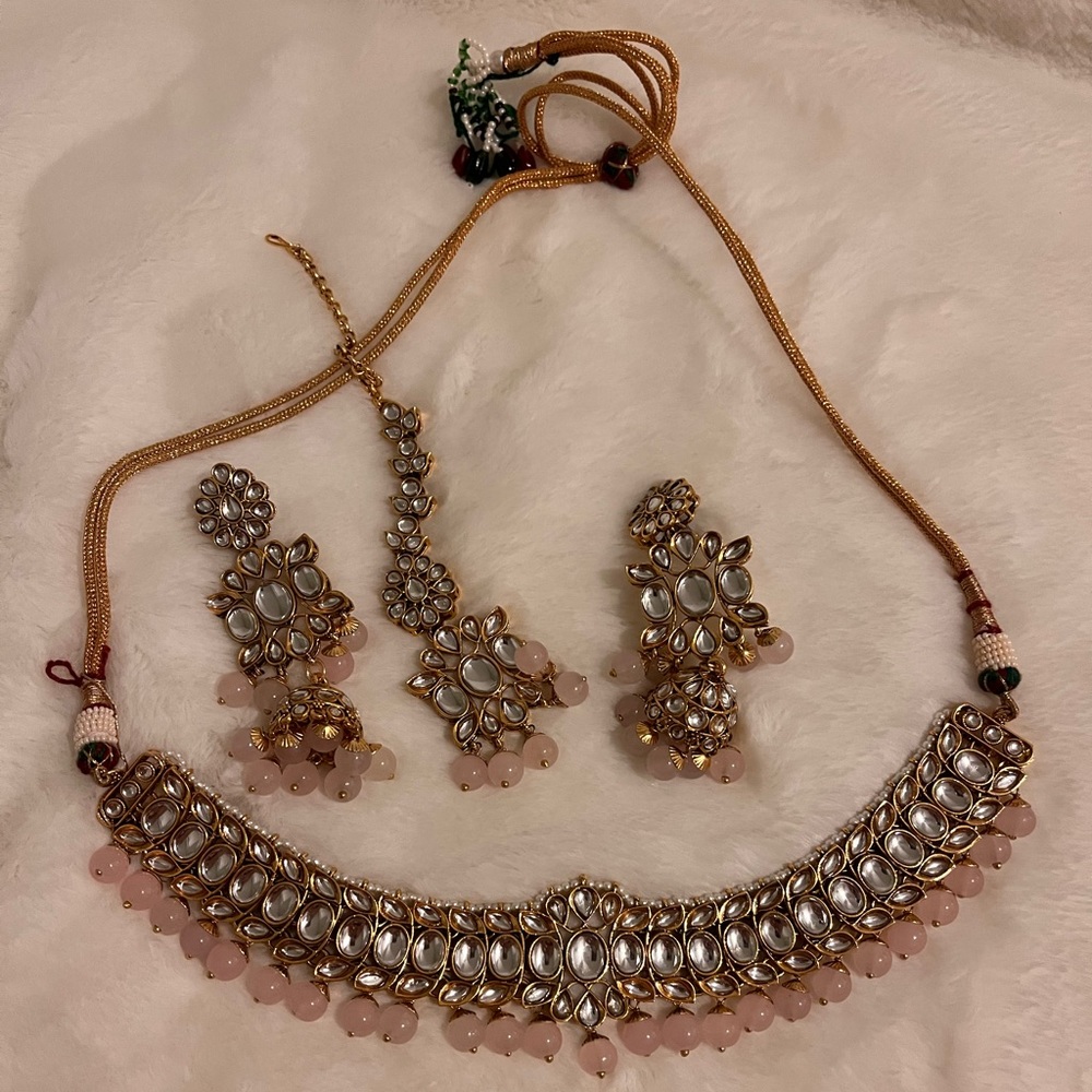 Light pink kundan set with earrings, necklace, and tikka